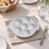 Empty white six-well escargot dish in an appetizer table setting