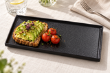 11¾″ × 6½″ Textured Black Ceramic Stackable Rectangular Plate with avocado toast and tomatoes; table accessories shown separately