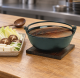 15 cm iron nabe pot with wood lid beside prepared vegetables