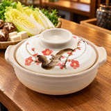 Cream clay donabe with red blossom decoration beside prepared vegetables