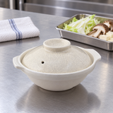 Small cream crackle-glaze donabe beside prepared vegetables