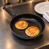 Joycook Durastone Marble Cast Aluminum Frying Pan 8" with a finished food preparation on a restaurant counter