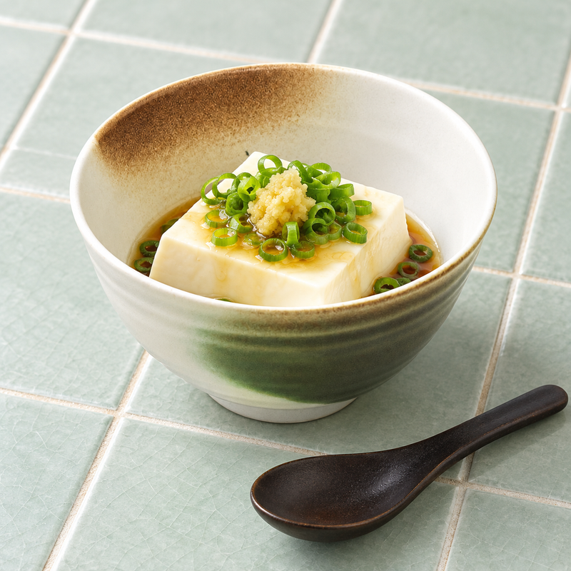 Green and brown accent rice bowl holding tofu with scallions and sauce