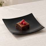 Black square flare plate with a brownie and raspberries