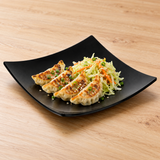 Black square flare plate with gyoza and cabbage slaw