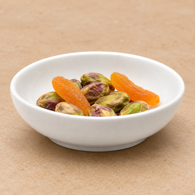 Pistachios and dried apricots inside the plain white J5544 round ceramic sauce plate