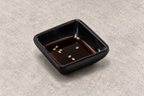 334-AB: Melamine Square Sauce Dish 3", Black. Restaurant serving context