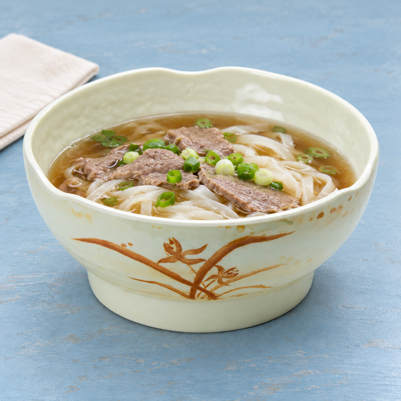 Gold Orchid bowl holding noodle soup topped with sliced beef and scallions.