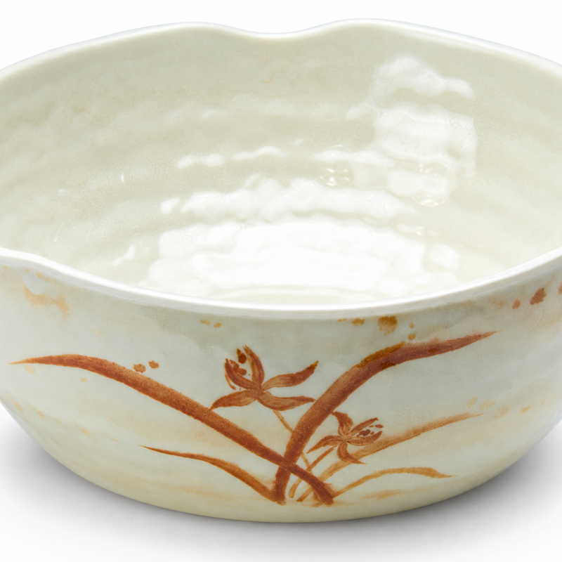 Detail of the waved rim, dimpled interior and orchid decoration on a cream-beige bowl.