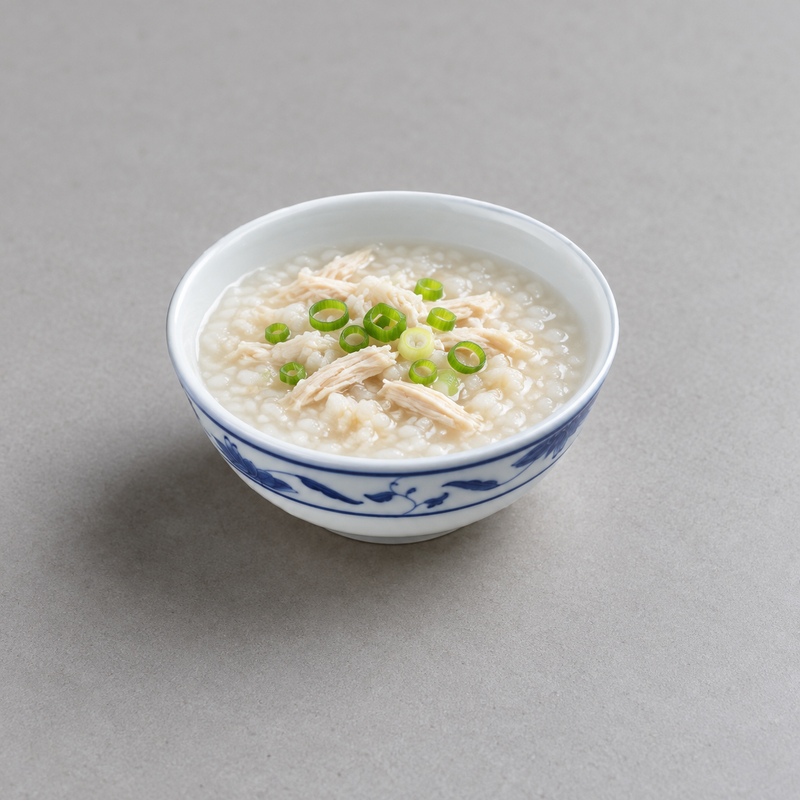 Blue Lotus bowl holding chicken congee topped with scallions.