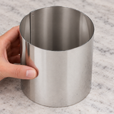Hand steadying empty Paderno 47534-07 tall stainless steel pastry ring on a worktop