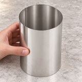Hand steadying empty Paderno 47534-09 tall stainless steel pastry ring on a worktop