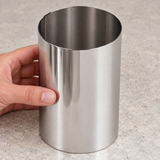 Hand steadying empty Paderno 47534-10 tall stainless steel pastry ring on a worktop