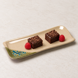 Two chocolate cake squares with chocolate shavings and two raspberries on the 510-M long rectangular patterned plate.