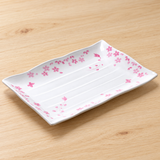 White rectangular plate with pink blossoms and a ribbed well on a pale wooden table
