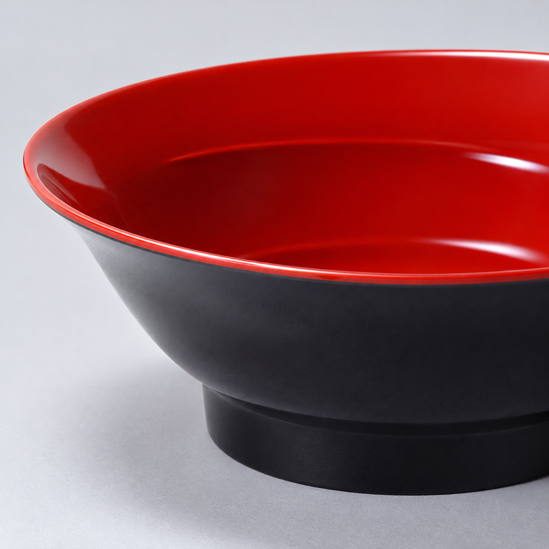 Close-up of the flared red rim and black footed body of the udon bowl.
