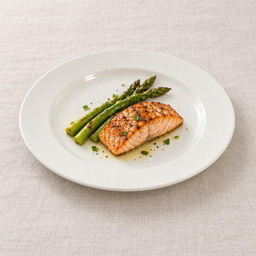 White broad-rim ceramic plate with salmon and asparagus