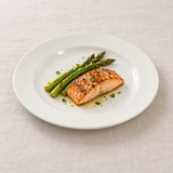 White broad-rim ceramic plate with salmon and asparagus