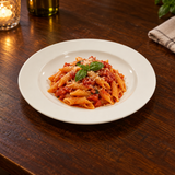 White broad-rim ceramic plate with tomato penne