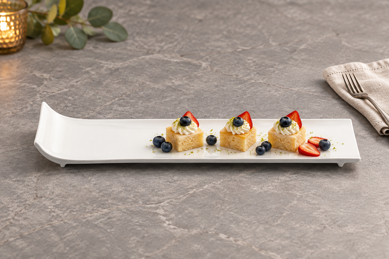 A15649 white raised-end rectangular plate with petite cakes and berries on a gray table