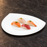 A2018 white ceramic triangular plate with a small nigiri assortment on a restaurant tabletop; food not included.