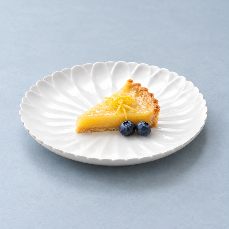 A4276 flower-relief plate with a yellow tart slice, citrus peel and blueberries as a serving suggestion.