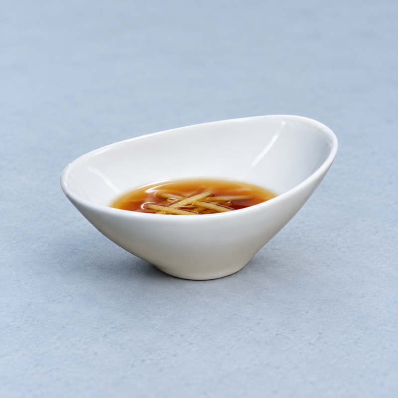 A4822 slanted white ceramic bowl holding a ginger-garnished dipping sauce on a blue tabletop