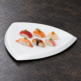 A6956 white ceramic triangular plate with a small nigiri assortment on a restaurant tabletop; food not included.