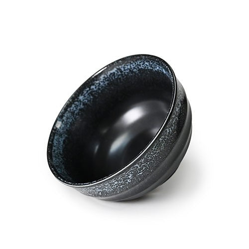 Black ceramic bowl with a dark interior and pale speckled upper rim