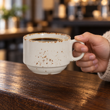 Splash Blanch 8 oz porcelain cup held by its handle with coffee