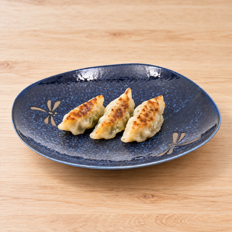 BD28-N navy Dragonfly ceramic plate with three vegetable gyoza on a light wooden table