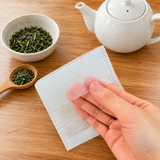 An empty BT4 filter bag held beside separate loose tea, a spoon and a teapot