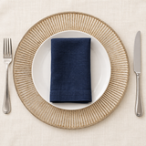 Antique silver radiant charger beneath a separate white plate and navy napkin, with flatware alongside