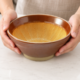 G56-K ridged grinding bowl steadied by two hands with its empty interior visible