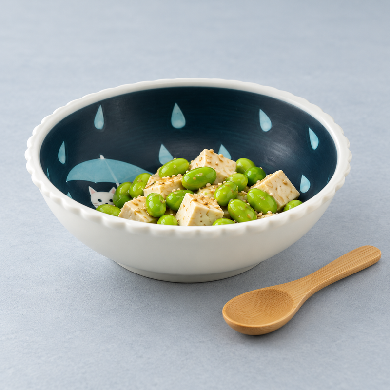 Shallow white scalloped bowl with a deep blue raindrop interior holding a small green salad with pale cubes.