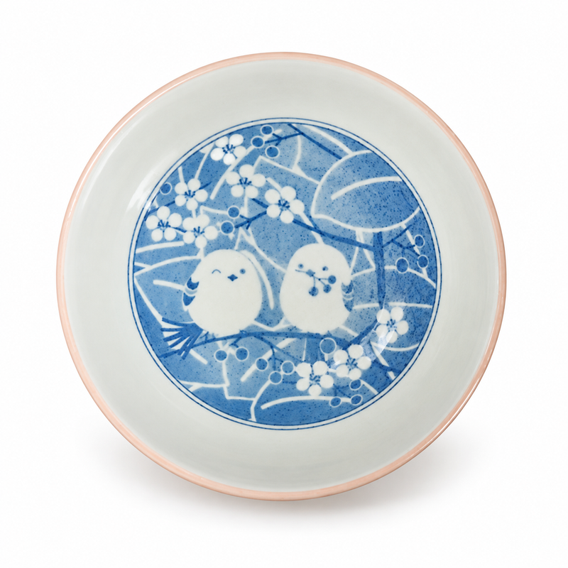 Pink-rimmed sparrow bowl viewed from above, with a pale interior and blue circular bird-and-blossom illustration.
