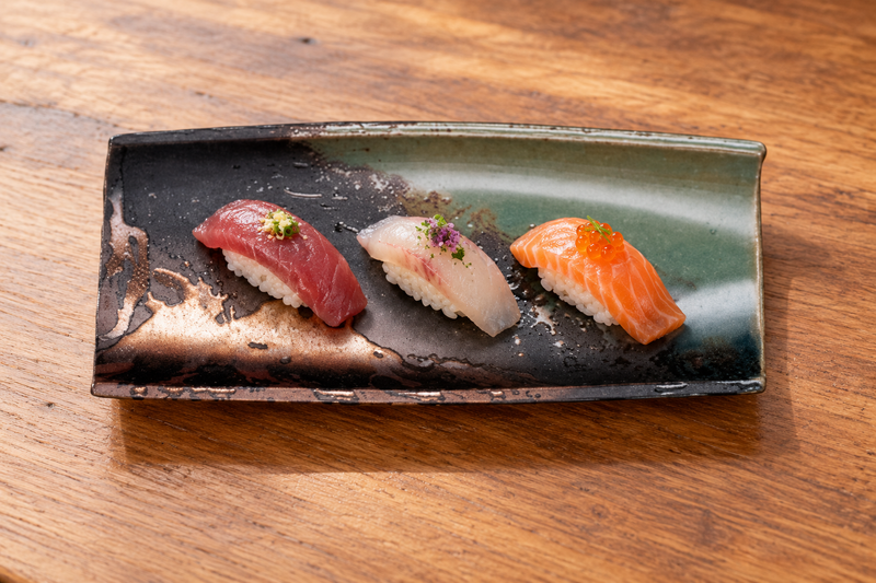 IM411-IK with three nigiri on a wood tabletop