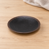 Black and brown round plate in a natural tabletop setting