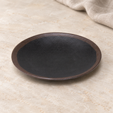 Black and brown round plate in a natural tabletop setting