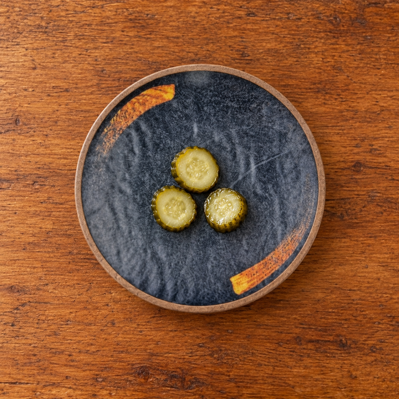 7-inch round melamine plate with a small pickle serving