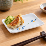 JSQ506B-HM Rain Flower rectangular plate with gyoza and cucumber on a light wood counter