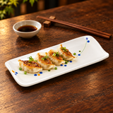 JSQ510-HM005 Rain Flower long rectangular plate with gyoza on a dark wood table