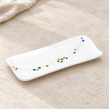 White rectangular floral-vine plate in a natural tabletop setting