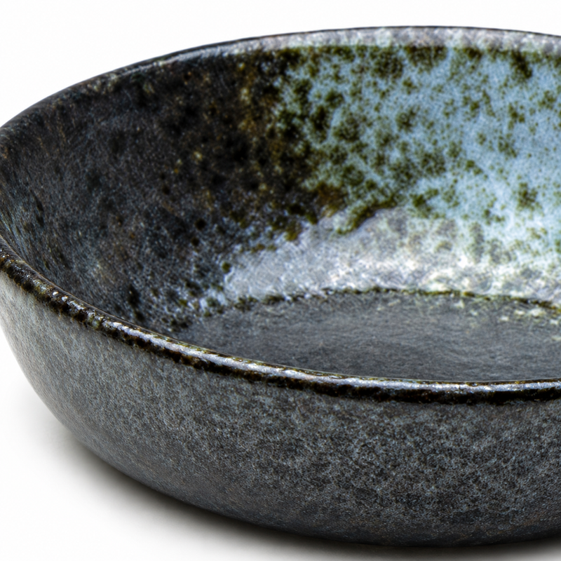 Close view of the JX-26-B shallow Black Oribe porcelain bowl showing its dark surface and pale mottled green-gray interior accent.