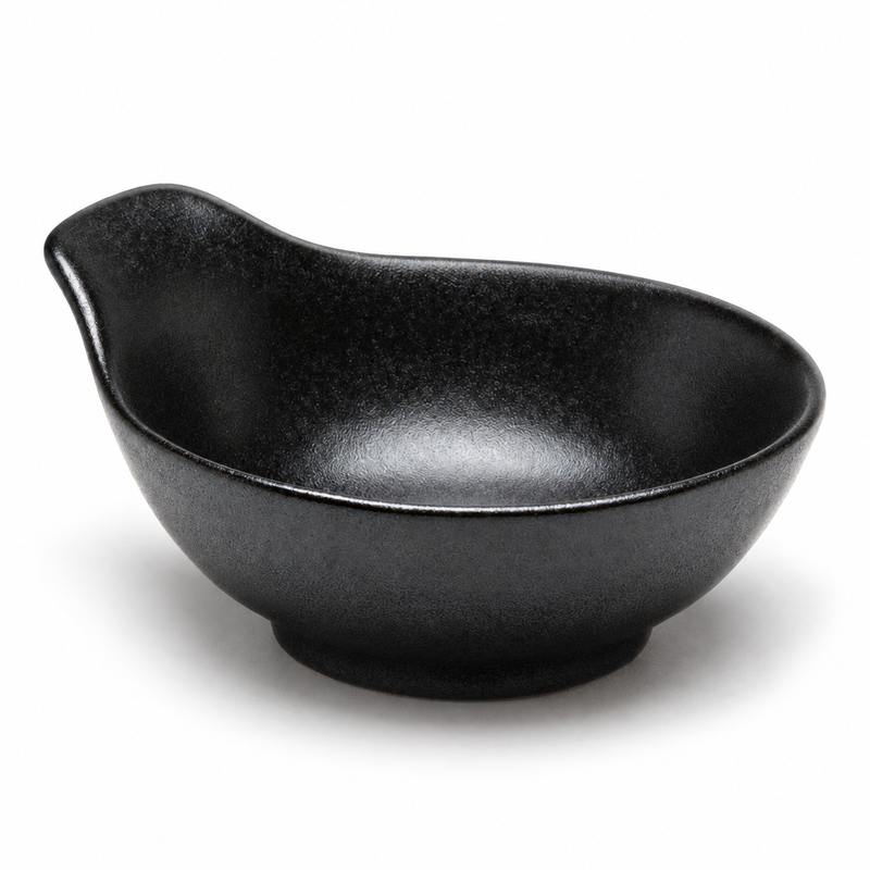 Matte-black porcelain sauce bowl with a broad raised tab handle, shallow round well and short foot.