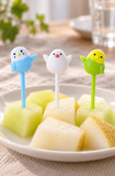Three raised-wing bird picks with stems inserted into small fruit portions
