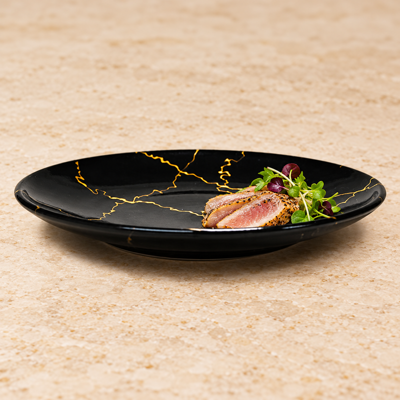 K210-LIT1 black ceramic plate with gold-colored lines and a fish serving