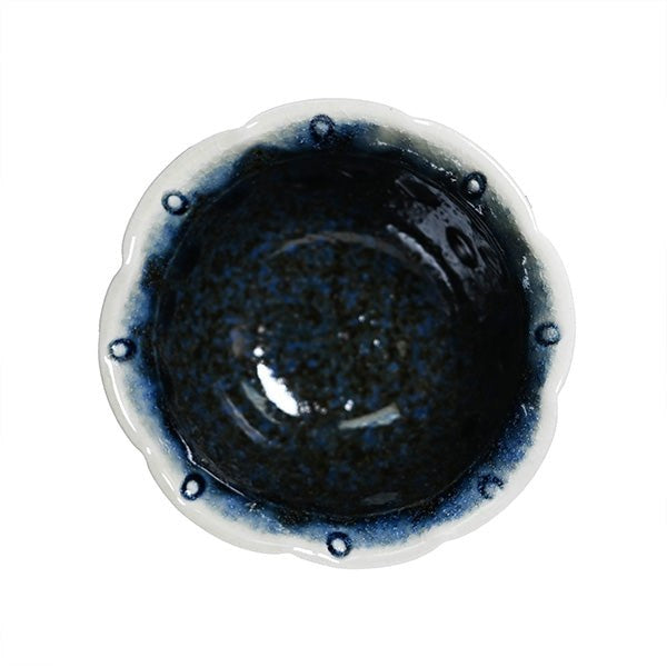 Authentic overhead view of a dark navy ceramic bowl with a pale scalloped rim and dark oval accents.