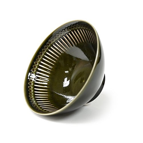 Tilted view of the olive-green bowl with pale radial lines and circular motifs below a dark rim.
