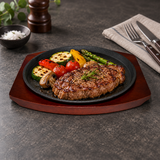 NTP-05 round iron steak plate with wood base — steak and vegetables serving suggestion